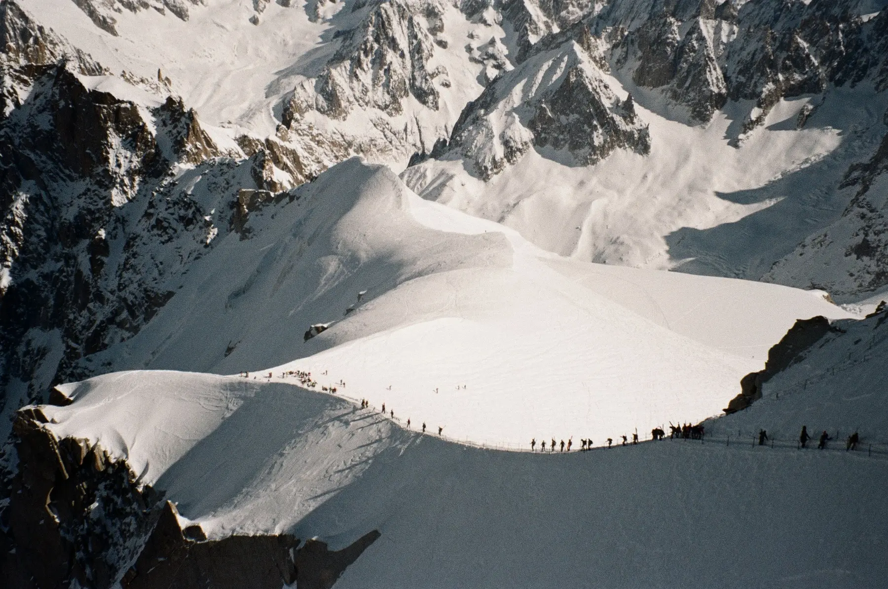 Snow-covered mountain ridge with a line of people crossing