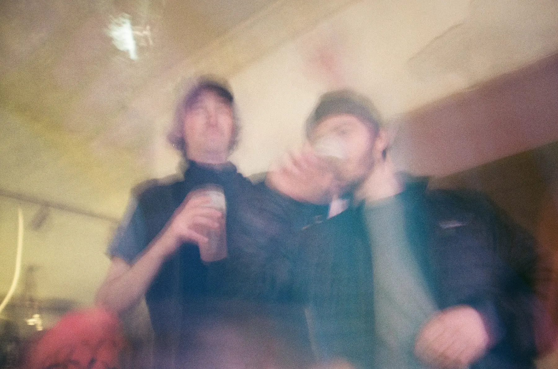 Two blurred figures at an indoor gathering