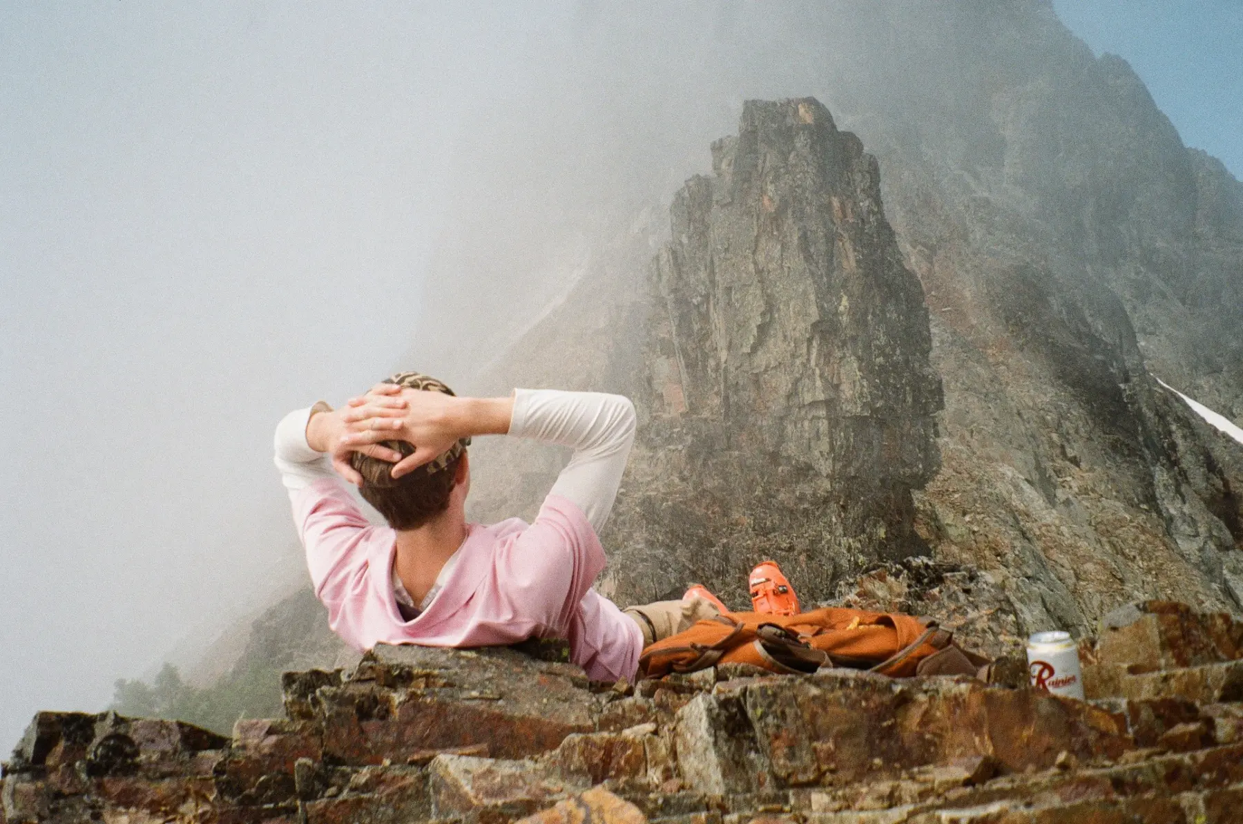 Climber resting beneath a misty mountain face