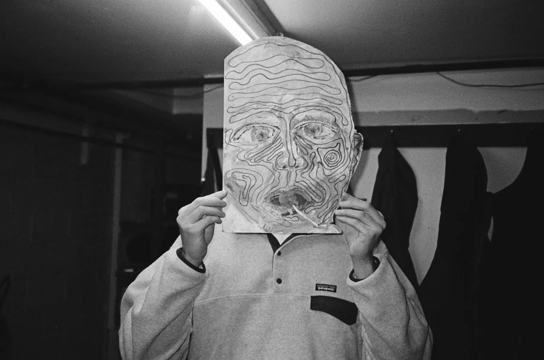 Person holding a hand-drawn face in front of their own
