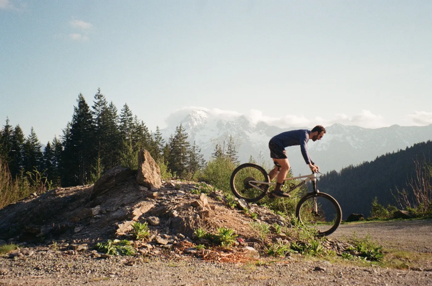 Mountain biker descending with snowy peaks behind