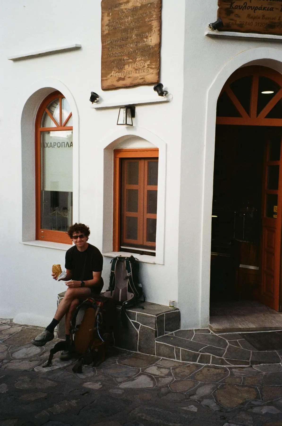 Traveler eating outside a white building in Greece