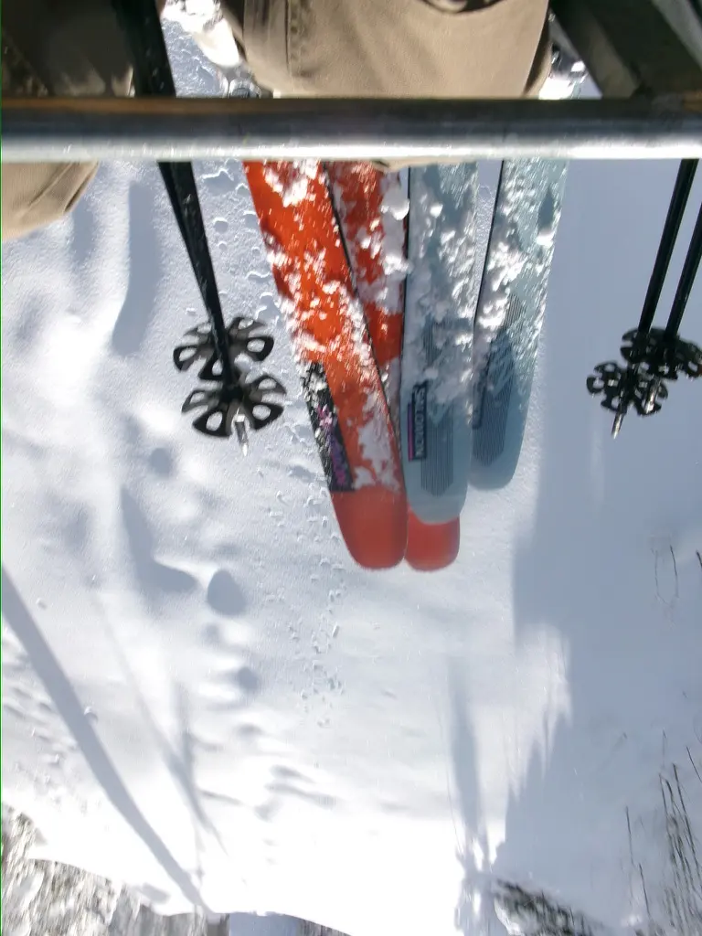 Skis and poles seen from a chairlift above fresh snow