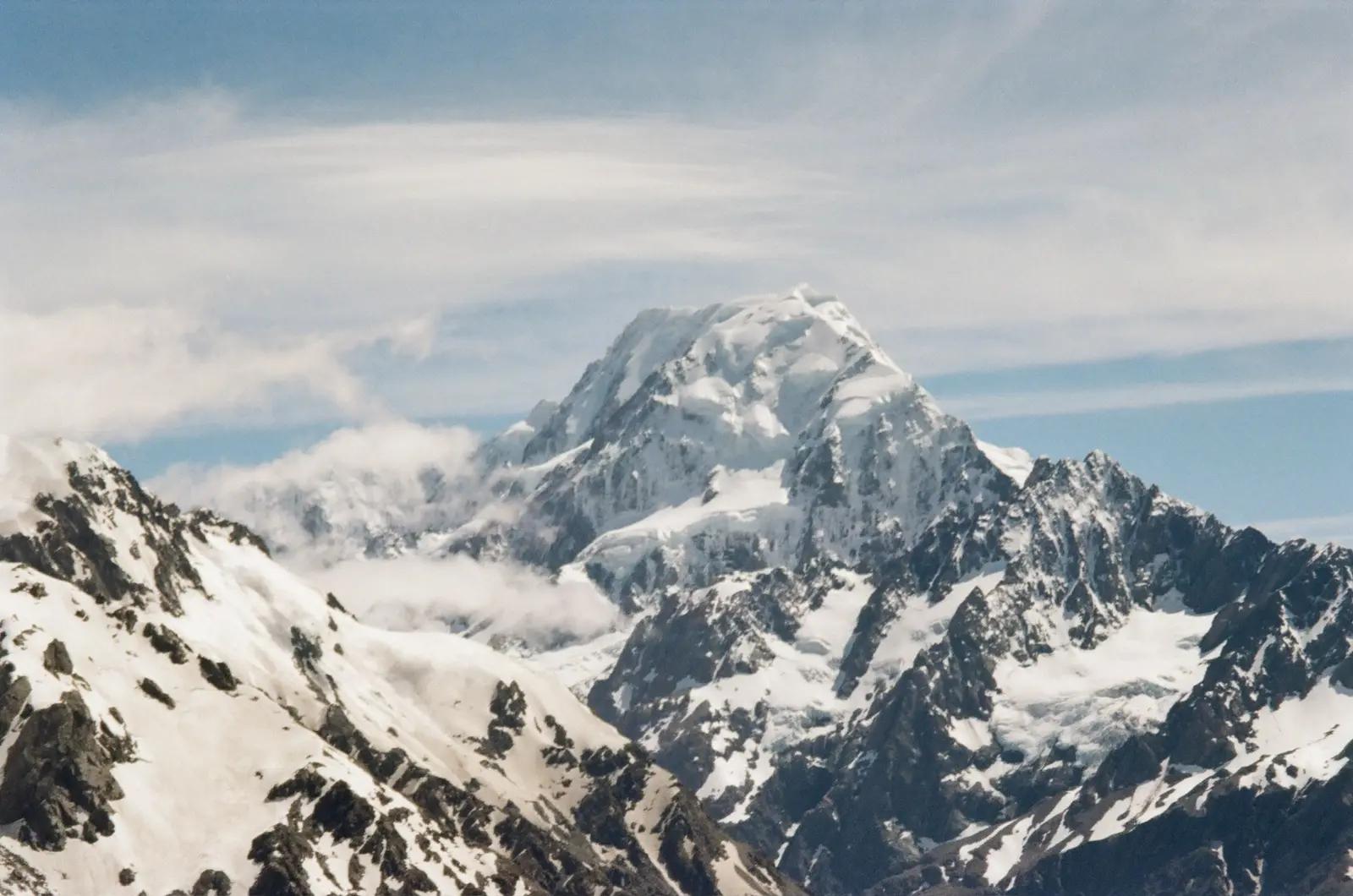 Snow-covered mountain peak beneath a pale blue sky