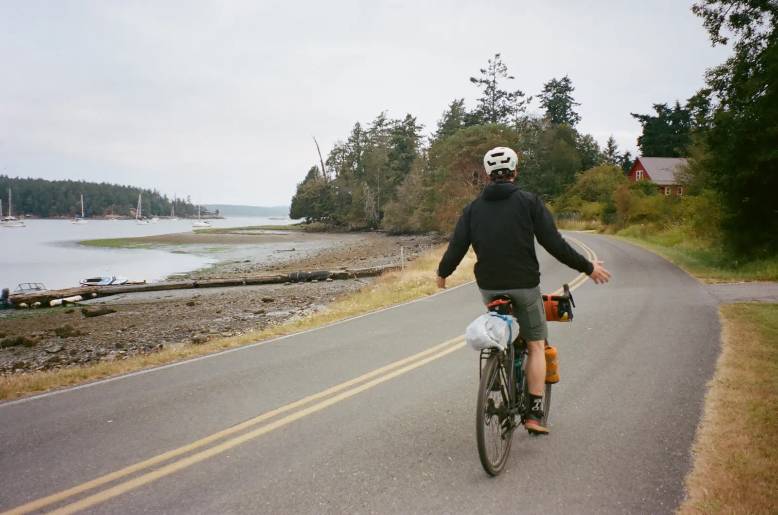 Bike traveler riding away along a coastal road