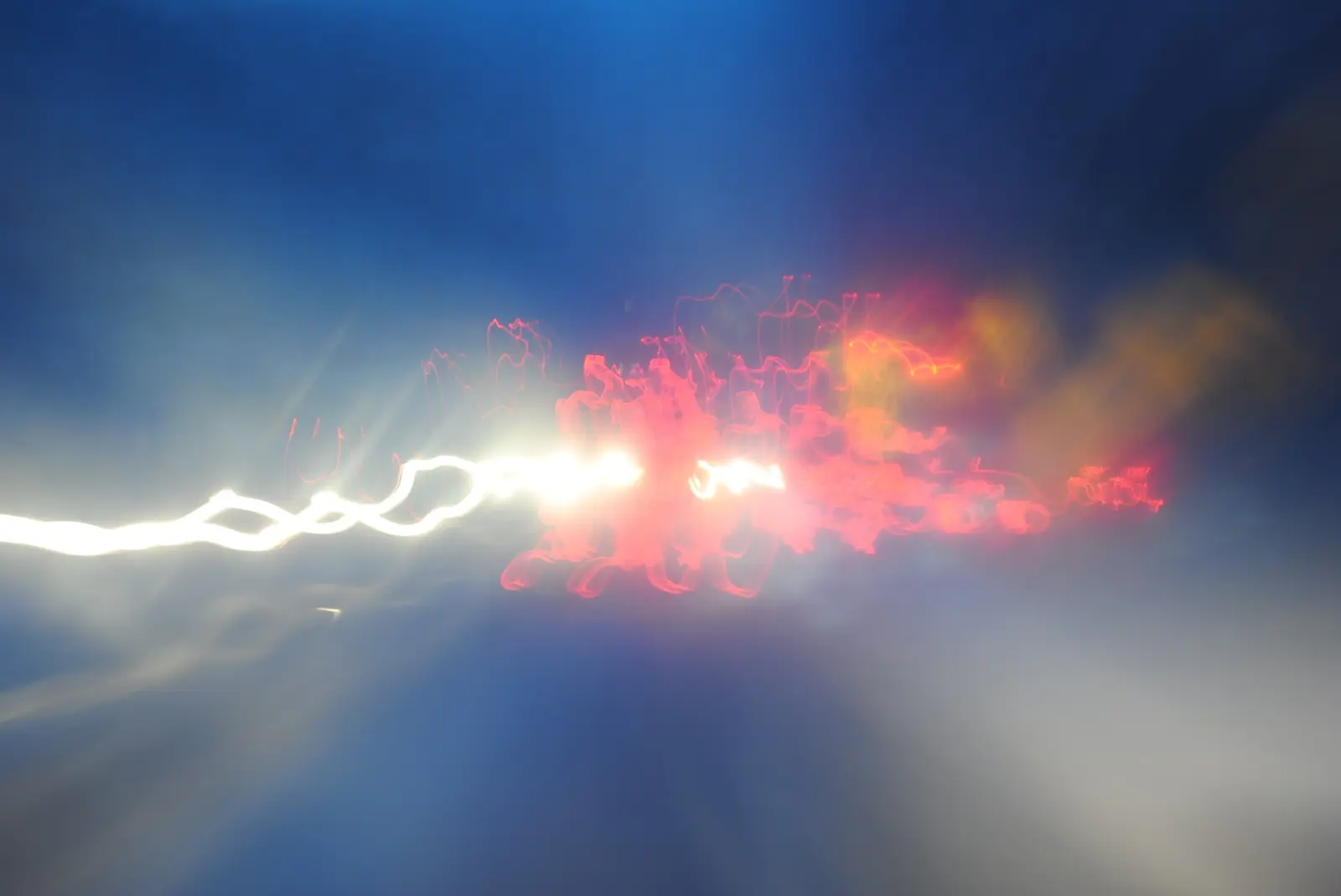 White and red light trails blooming against a blue night sky