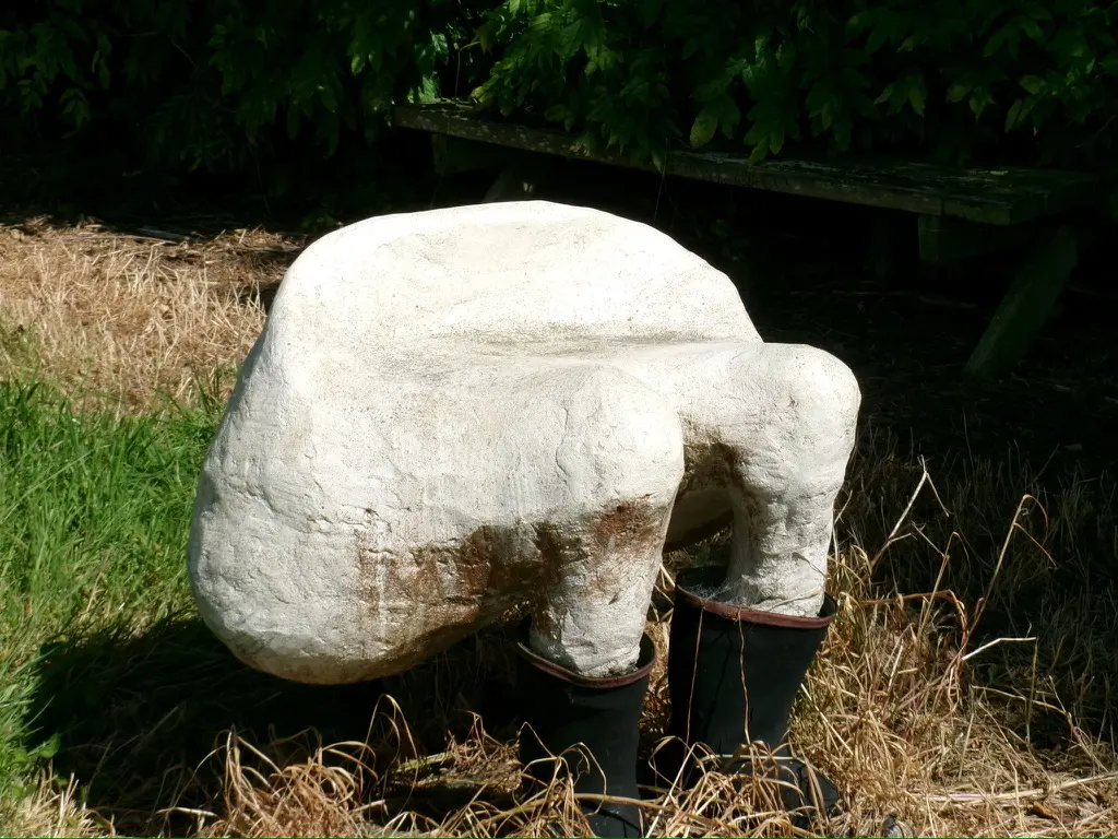 White garden sculpture wearing black rubber boots