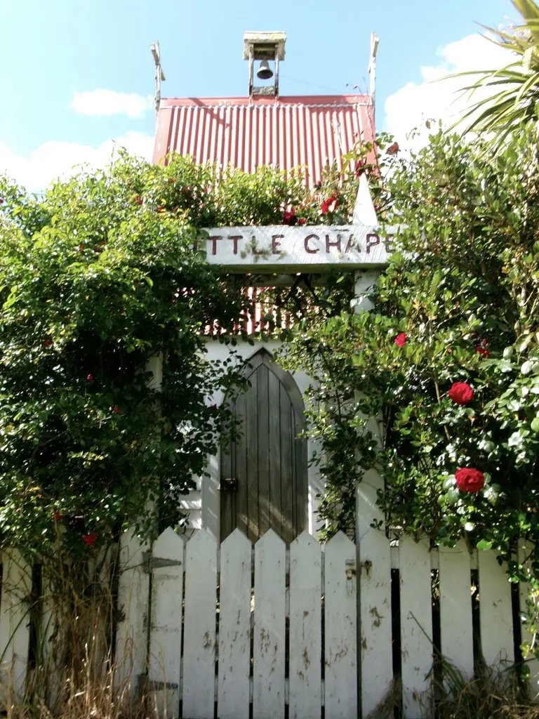 Small chapel framed by flowers and a white picket fence
