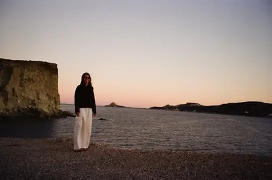 Person standing on a quiet beach at dusk