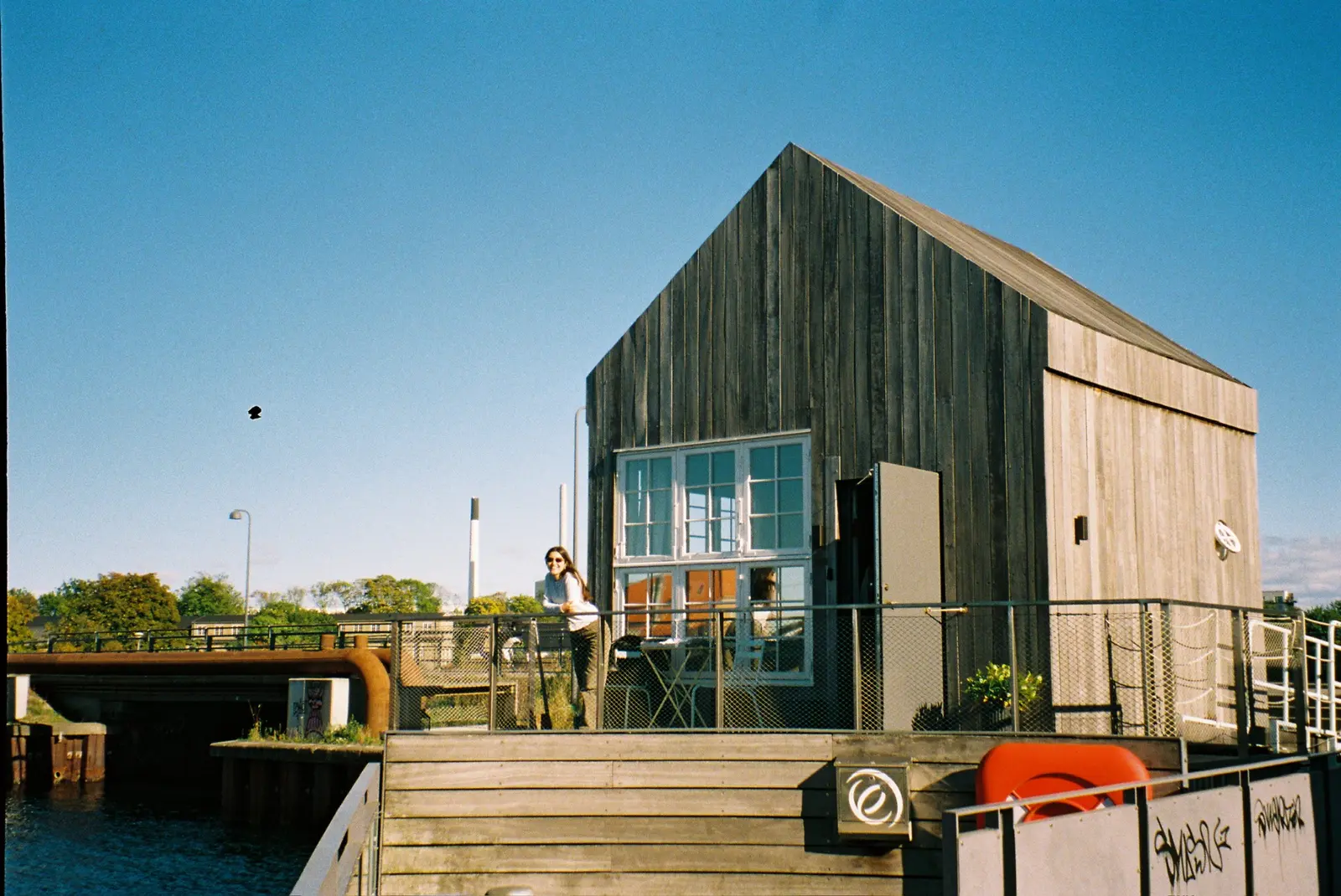 Person leaning on a railing beside a modern harbor building